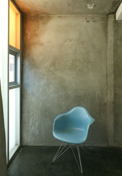 A composition with an Eames chair, a concrete wall, and orange glass is simple but strong; this photo by Claudio Santini shows a home designed by SPF Architects in Culver City, CA, using all recycled materials.