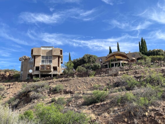 Distant view of clustered concrete structures perched on canyon edge amid desert vegetation