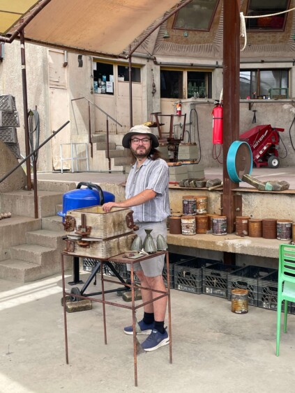 Person demonstrating metalworking process in industrial workshop space under concrete vault