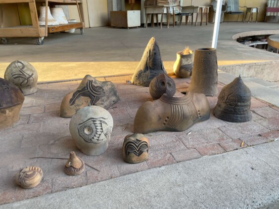 Display of colorful handmade ceramic bells in various sizes on retail shelving